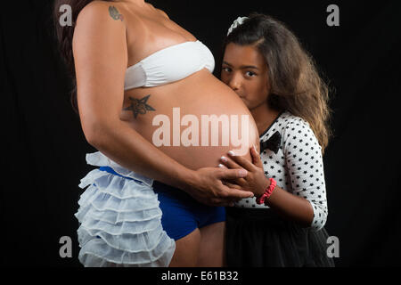 Mädchen küssen ihren Bauch der schwangeren Mutter Stockfoto