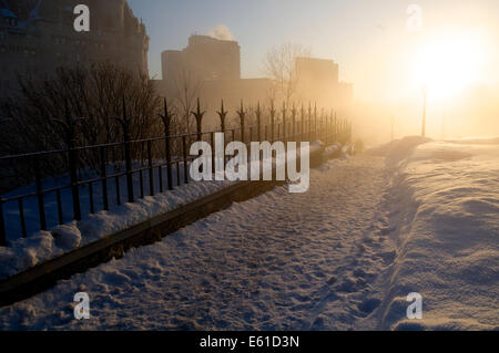 Morgensonne brennt durch Nebel im tiefen Winter auf dem Gelände der kanadischen Parlament (House Of Commons) entlang eines Pfades. Stockfoto