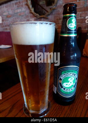 Ein Bierglas und eine Bierflasche mit Brooklyn Lager-Bier der Brauerei Brooklyn in New York, USA, 24. Juni 2014. Das Logo der Brauerei wurde von Milton Glaser, entworfen, auch das "I love NY"-Logo. Foto: Alexandra Schuler/Dpa - Achtung! KEIN KABEL-SERVICE- Stockfoto