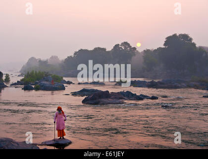 Hindu Guru grüßt die Sonne über Dschungel vom Ufer der Betwa Fluß in Indiens Orchha spähen. Stockfoto