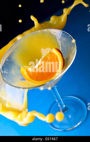 Cocktail mit Orange im Glas mit Spritzern Nahaufnahme auf blauem Hintergrund Stockfoto