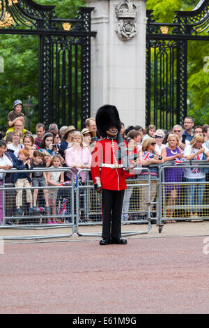 Grenadier-Fuß Wache stehenden Aufmerksamkeit mit Touristen, die gerade auf die Trooping die Farbe Parade, The Mall, London Stockfoto