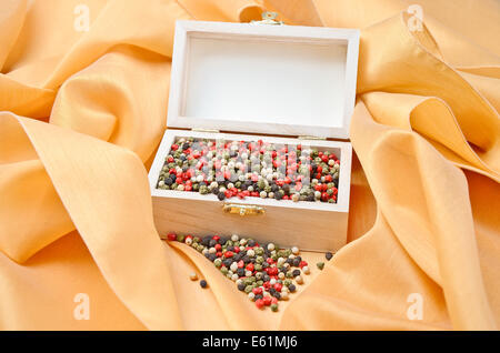 Schatz - gemischte Pfeffer getrockneten Pfefferkörner in einer Holzkiste auf Creme farbige Seide. Stockfoto
