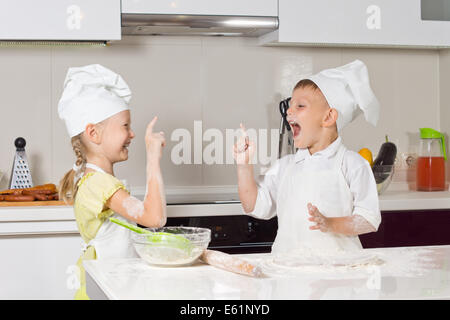 Sehr gerne kleine Kinder in der Köche Kleidung spielen in der Küche Stockfoto