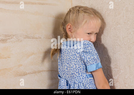 Niedliche kleine geflochtene Haar Mädchen in blau und weißes Kleid isoliert auf Holzwände Stockfoto
