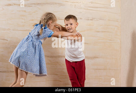 Niedliche kleine weiße Kinder spielen zu Hause isoliert auf leichten braunen Holzwänden Stockfoto