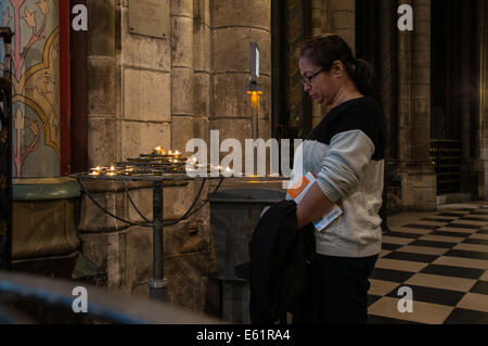 Touristischen Frau betrachten brennende Kerzen im Inneren der Kathedrale Notre Dame in Paris, Frankreich Stockfoto