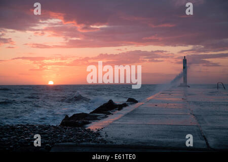 Aberystwyth, Wales, UK. 11. August 2014. Gepeitscht bis durch den Sturm namens Bertha Meer stürzt Wellen gegen den Leuchtturm in Aberystwyth bei Sonnenuntergang. Bildnachweis: Jon Freeman/Alamy Live-Nachrichten Stockfoto