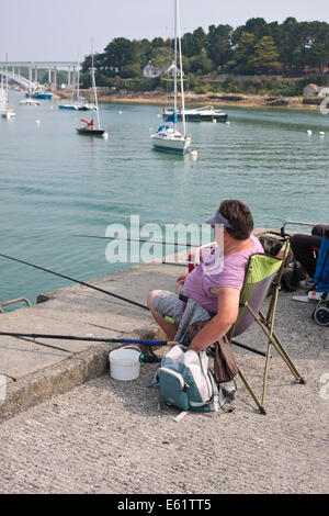 Eine Frau Angeln auf Meeräsche an der Pier in La Trinité-Sur-Mer, Bretagne, Frankreich Stockfoto