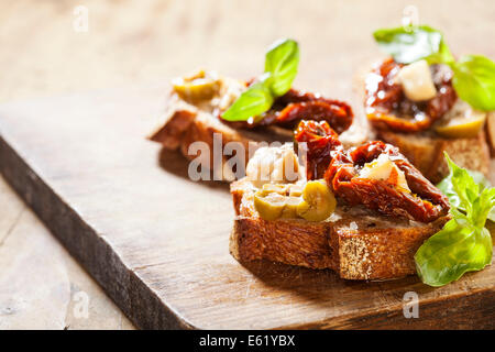 Italienische Vorspeise Bruschetta mit Olivenöl, Oliven, getrocknete Tomaten und Käse. Stockfoto