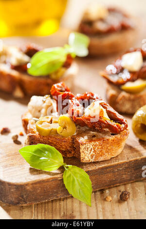 Italienische Vorspeise Bruschetta mit Olivenöl, Oliven, getrocknete Tomaten und Käse. Stockfoto