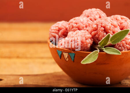 Rohe Frikadellen mit Salbei auf warmen hölzernen Hintergrund Stockfoto