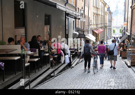 Leben auf der Straße im alten Stockholm mit Bürgersteig Restaurants, Coffee-Shops, Fußgänger und Musikern entlang der gepflasterten Straßen Stockfoto