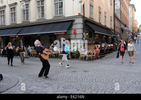 Leben auf der Straße im alten Stockholm mit Bürgersteig Restaurants, Coffee-Shops, Fußgänger und Musikern entlang der gepflasterten Straßen Stockfoto