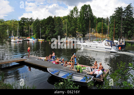 Ausflugsboote und Kajakfahrer auf Långholmen Långholmen Kanal mit Sonnenanbeter in Stockholm Stockfoto