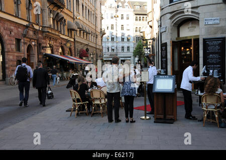 Leben auf der Straße im alten Stockholm mit Bürgersteig Restaurants, Coffee-Shops, Fußgänger und Musikern entlang der gepflasterten Straßen Stockfoto