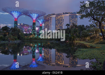 Skyline von Singapur Marina Bay Sands sowie Supertree Grove in der Abenddämmerung mit Reflexionen in einem Teich. Stockfoto