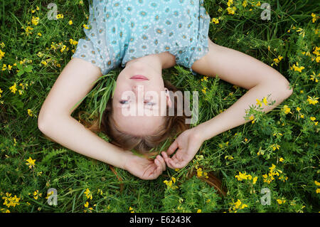 Porträt der jungen Frau in einem Feld von Blumen liegen auf den Kopf Stockfoto