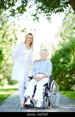 Hübsche Krankenschwester kümmert sich um ältere Patienten beim Spaziergang im park Stockfoto