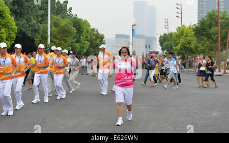 (140812)--NANJING, Aug.12, 2014 (XINHUA)--Fackelträger Gulmira Mitigo La hält die Flamme während der Fackellauf der Nanjing 2014 Youth Olympic Games in Nanjing, der Hauptstadt der ostchinesischen Provinz Jiangsu, auf August.12, 2014.Nanjing 2014 Olympischen Jugend-Winterspiele von 16 bis 28 August stattfinden wird. (Xinhua/Li Xiang) Stockfoto