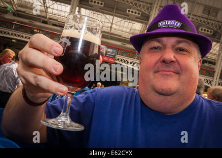 Olympia, London, UK. 12. August 2014. Ein Besucher der CAMRA Great British Beer Festival wirft sein Glas über 900 Ale, Bier und Apfelwein an Londons Olympia Exhibition Centre ausgestellt sind. Bildnachweis: Paul Davey/Alamy Live-Nachrichten Stockfoto