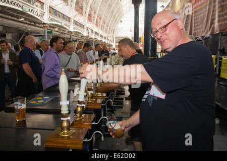 Olympia, London, UK. 12. August 2014. Lebhaftes Geschäft erfolgt an der Zapfsäule, wie Hunderte von Menschen 900 verschiedene Ales, internationale Biere, Apfelwein und Birnenmoste an der CAMRA Great British Beer Festival probieren. Bildnachweis: Paul Davey/Alamy Live-Nachrichten Stockfoto