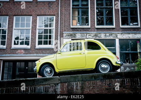 Gelb/grün Fiat 500 parkte auf einem Kanalufer in Amsterdam, Niederlande Stockfoto