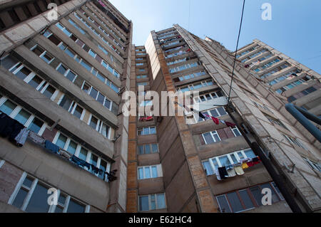 Die Wäscherei hängt von Balkonen von hoch aufragenden Wohnblöcken aus der Sowjetzeit vor blauem Himmel, Jerewan, Armenien Stockfoto