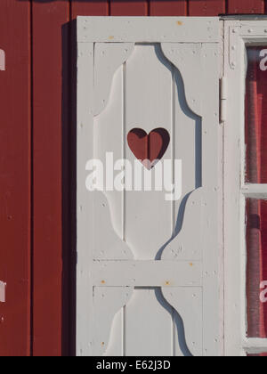 Detail der weiße Holzfenster Verschluss mit geschnitzt Herz auf roten Wand, Norwegen Stockfoto