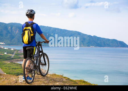 jungen Mann, der auf dem Berg mit Fahrrad Stockfoto
