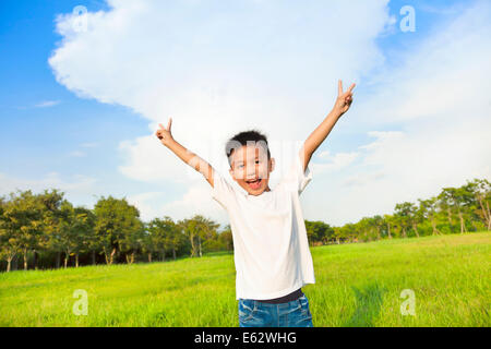 glückliche Kinder stehen auf der Wiese und heben die Hände Stockfoto