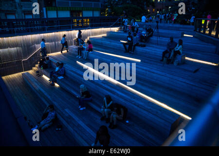 Manhattan, New York. Leute sitzen in der Abenddämmerung auf der Anzeige ein Ansporn der Highline Park am 26th Street. Stockfoto