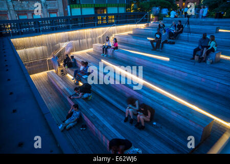 Manhattan, New York. Leute sitzen in der Abenddämmerung auf der Anzeige ein Ansporn der Highline Park am 26th Street. Stockfoto
