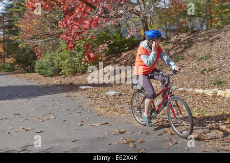 Eine junge Frau fährt Fahrrad während des Gesprächs auf dem Handy Stockfoto