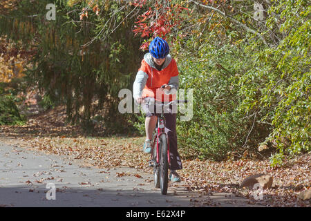 Eine junge Frau fährt Fahrrad während SMS auf ein Handy Stockfoto