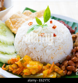 Nasi Lemak Kukus traditionelle malaysische würziges Reisgericht. Serviert mit Belacan, Ikan Bilis, Acar, Erdnüssen und Gurken. Stockfoto