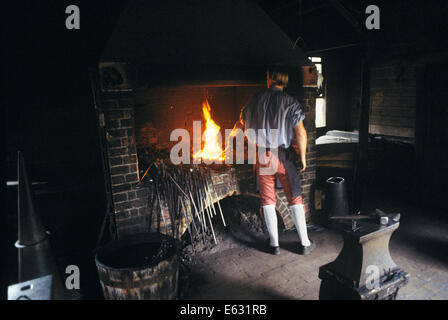 ANONYME SCHMIED TRÄGT KOLONIALE KLEIDUNG ZURÜCK ZU KAMERA HOLDING EISEN SCHMIEDE WILLIAMSBURG VA USA Stockfoto