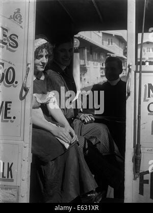 1900 S-1910 S 1920ER JAHRE WEHMÜTIGEN JUNGE FRAU SITZT IN DELIVERY WAGON MIT ANONYMEN MANN STUMMFILM NOCH Stockfoto