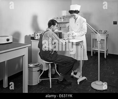 1940S 1950S KRANKENSCHWESTER UNTERSUCHEN VERLETZUNGEN AN HAND DES MENSCHEN IM WERK KRANKENSTATION Stockfoto