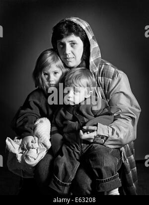 1960ER JAHRE PORTRAIT OBDACHLOSEN ARMUT GEPLAGTEN MUTTER UND IHRE ZWEI KINDER, SOHN UND TOCHTER BLICK IN DIE KAMERA Stockfoto