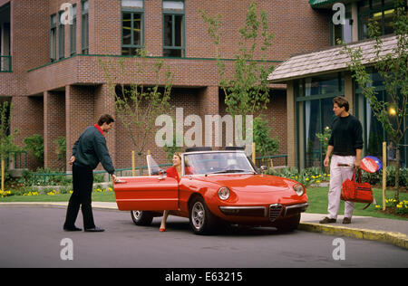 1990ER JAHRE PARKPLATZ VALET HÄLT TÜR FÜR MANN UND FRAU ENTRINDUNG VON SPORTWAGEN, TENNIS SPIELEN Stockfoto