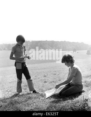 1970ER JAHREN ZWEI JUNGS IM FRÜHEN TEENAGERALTER MIT KITE IM FELD Stockfoto