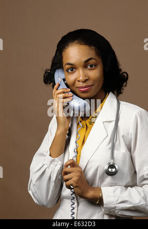 AFROAMERIKANISCHE FRAU ARZT TELEFONIEREN, BLICK IN DIE KAMERA Stockfoto