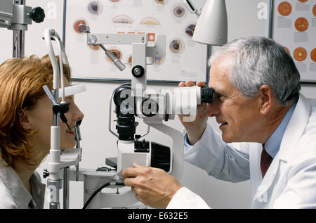 1990ER JAHRE ÄLTERE MÄNNLICHE OPTIKER PRÜFUNG ROTE KURZHAARIGE FRAU DER AUGEN Stockfoto