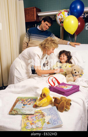 1980ER JAHREN VATER UHREN KRANKENSCHWESTER UNTERSUCHEN TOCHTER IM KRANKENHAUSBETT Stockfoto