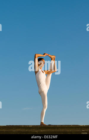 Junge Frau praktizieren Hatha Yoga im Freien, zeigen die Pose Utthita Hasta Pandangusthasana, hob die Hand zur Großzehe-pose Stockfoto