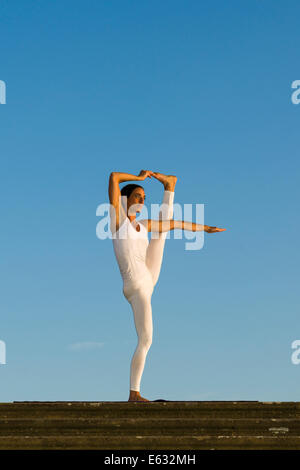 Junge Frau praktizieren Hatha Yoga im Freien, zeigen die Pose Utthita Hasta Pandangusthasana, hob die Hand zur Großzehe-pose Stockfoto