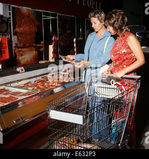 1970ER JAHREN ZWEI FRAUEN, MUTTER UND TOCHTER TREIBT EIN SHOPPING CART IN FLEISCH-ABTEILUNG DER SUPERMARKT Stockfoto