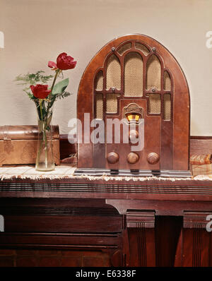 1930ER JAHREN STILLLEBEN DER KATHEDRALE STIL HOLZ CASE RADIO MIT GLASVASE MIT ROTEN ROSEN UND EIN KUPFER-BOX AUF MANTEL REGAL Stockfoto