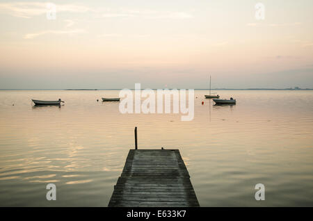 Alten Holzsteg mit verankerten Ruderboote am Abend in einer ruhigen Bucht Stockfoto